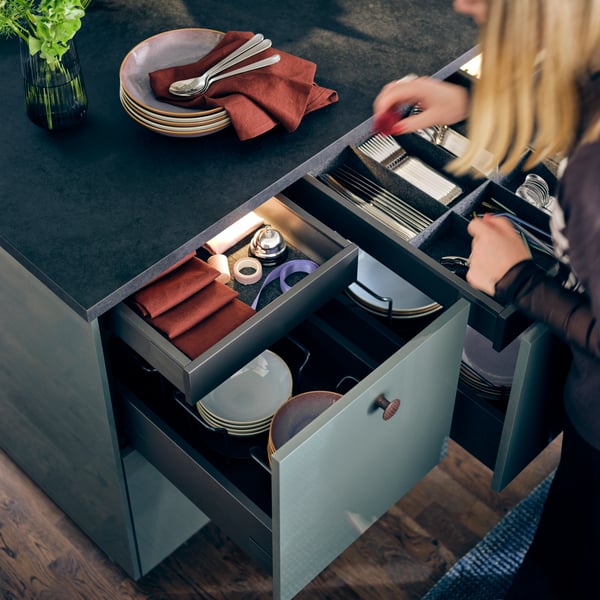 Une cuisine METOD avec des tiroirs KNIVSHULT, ouverts pour présenter des organisateurs de tiroirs UPPDATERA remplis d'ustensiles de cuisine.