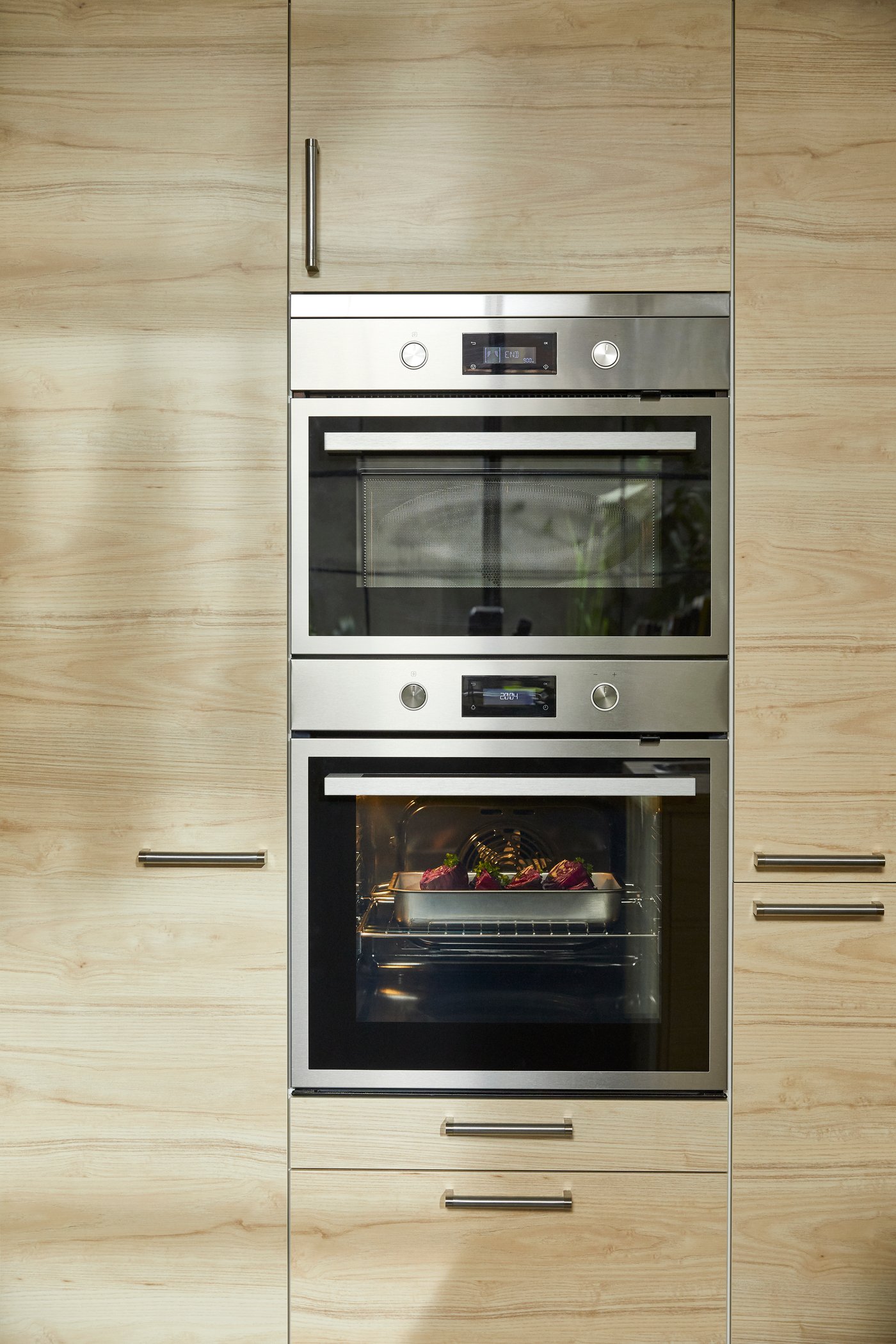 One larger oven and one smaller oven in black/stainless steel and drawer fronts and door fronts in light ash effect.