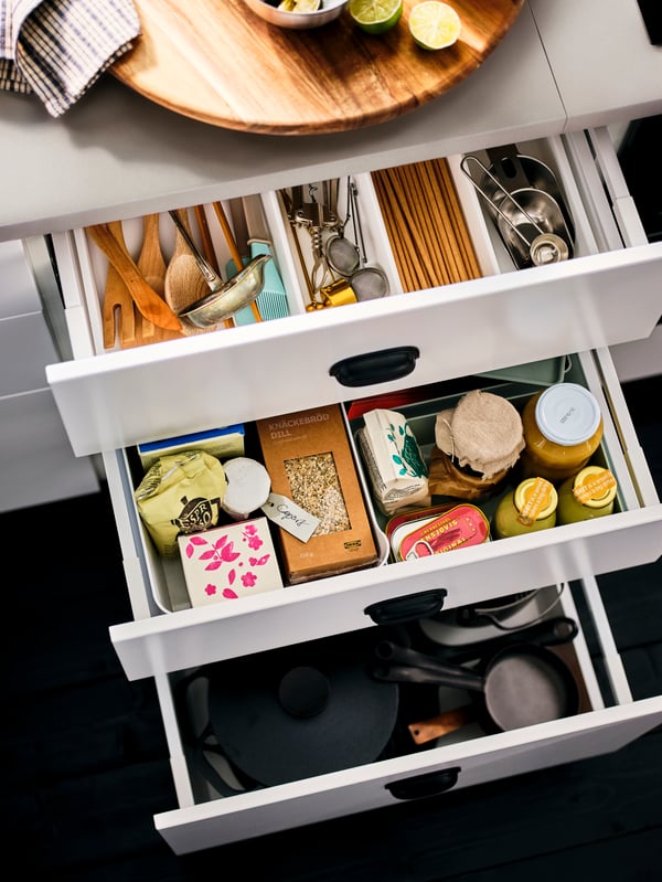 A column of drawn-out, white drawers, revealing neatly organised pantry-compatible bottles, jars and kitchen accessories.