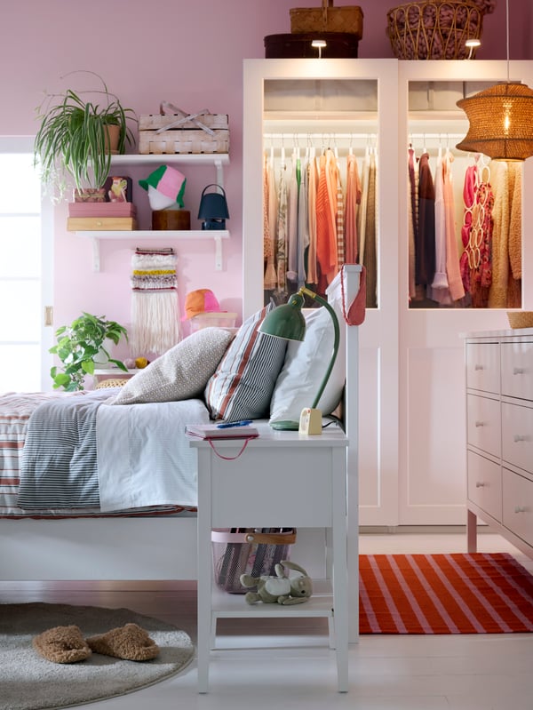 Bedroom with white HEMNES bed, GULLABERG bedside table and chest of drawers, pink walls and a PAX/GRIMO wardrobe in back.