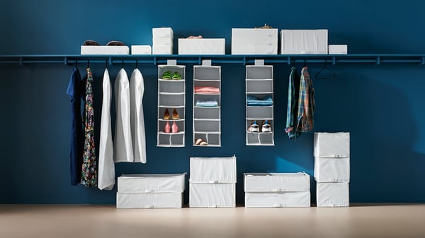 Una funda para ropa STUK blanca/gris en el dormitorio.