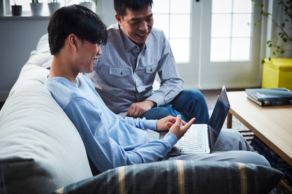 two people on a couch looking at laptop