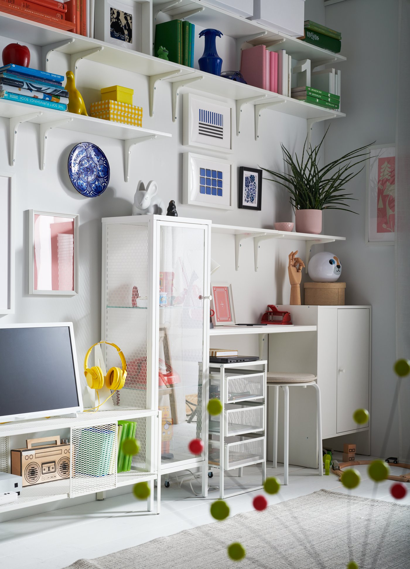 Moderner Arbeitsplatz mit IKEA-Wandregalen in Weiß und farbenfroher Dekoration. Regale gefüllt mit Büchern, Dekoartikeln und Aufbewahrungsboxen, kombiniert mit einem funktionalen Schreibtisch – ideale Lösung für ein kreatives Homeoffice.