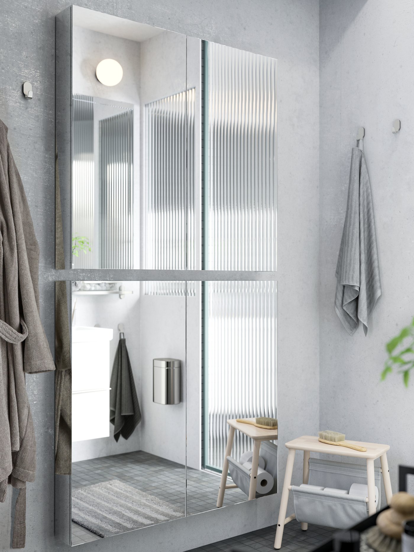 Zwei GODMORGON Spiegelschränke mit Türen hängen übereinander an einer hellgrauen Badezimmerwand.