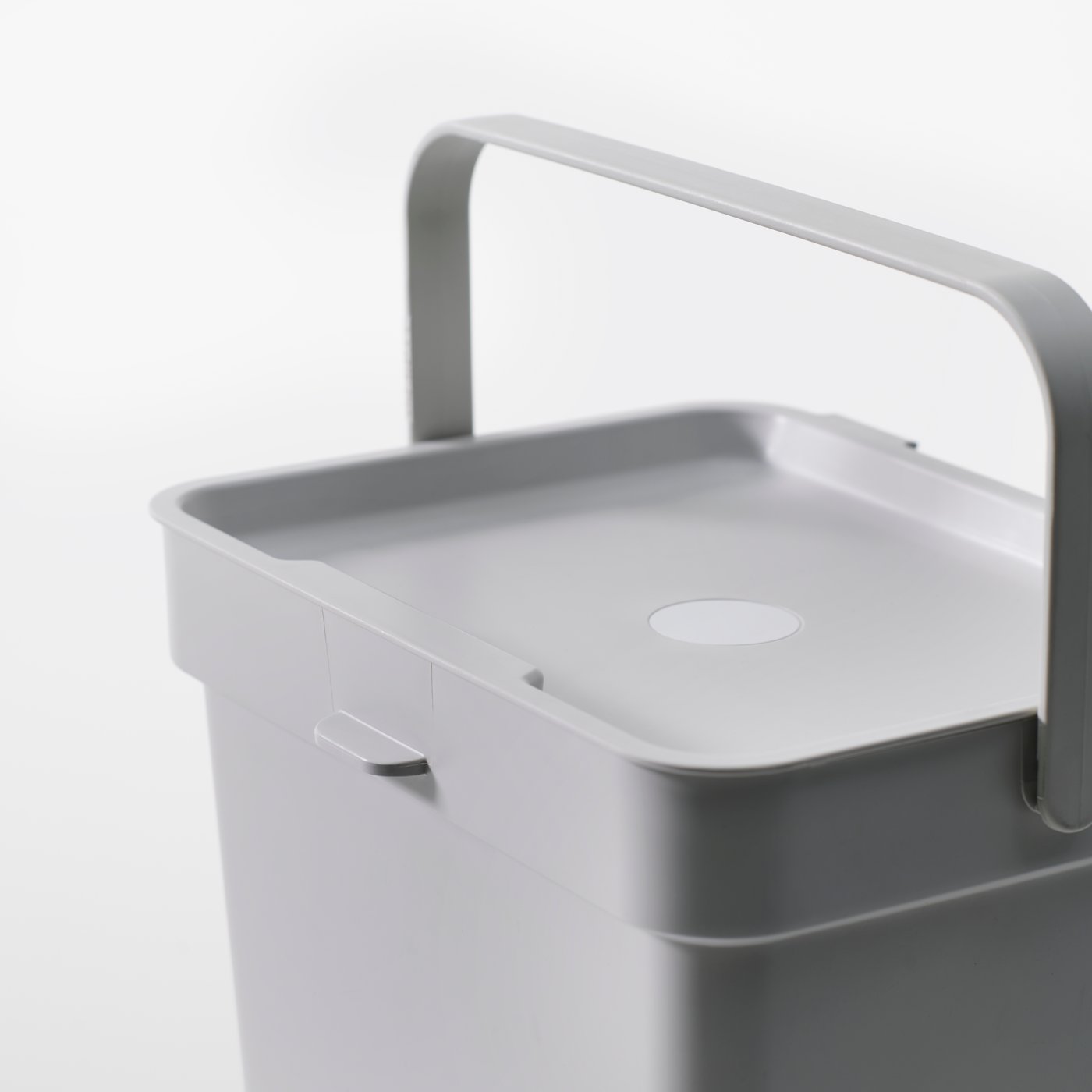 A close-up of a light grey HÅLLBAR bin with lid in a white studio space.