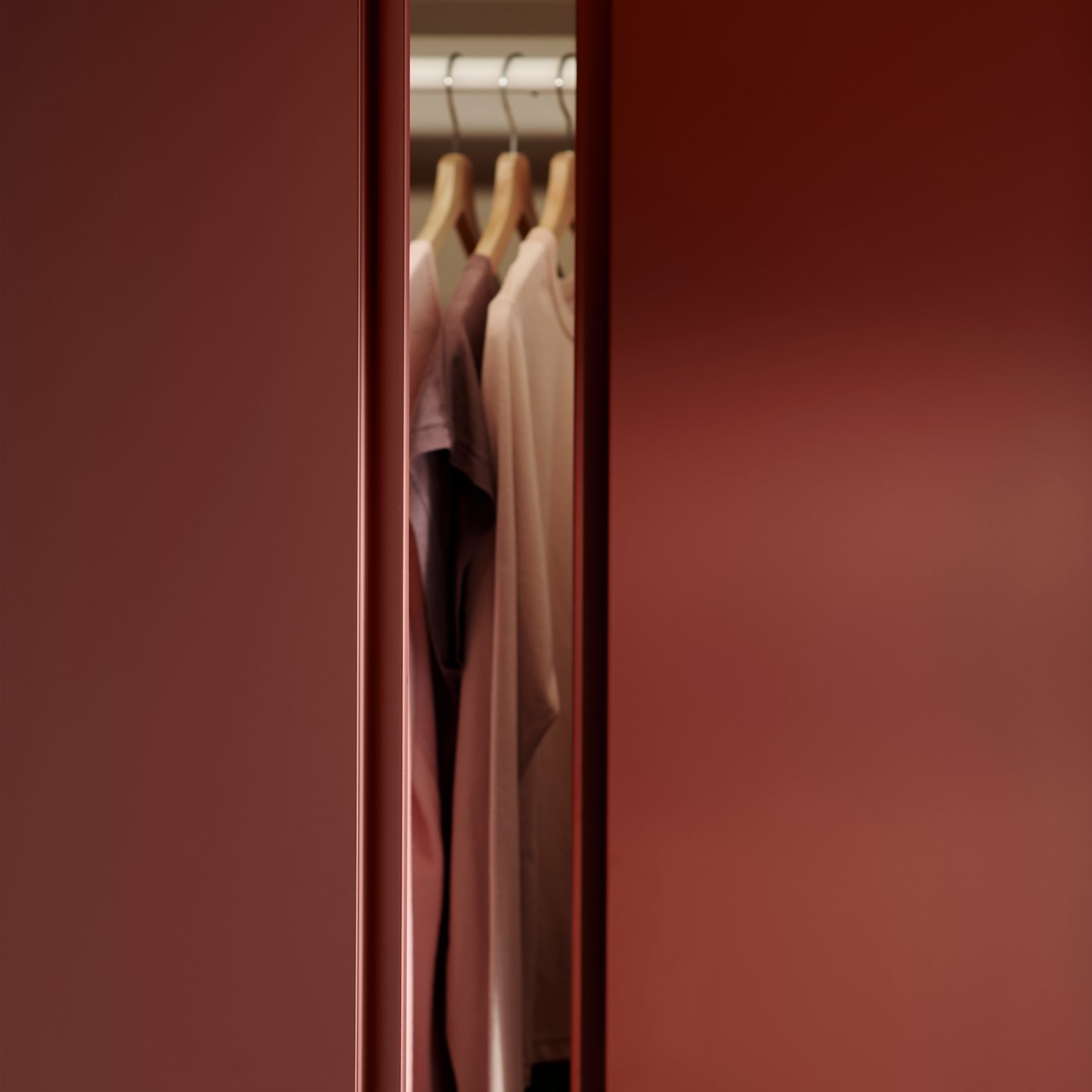 A close up of a PAX wardrobe with orange VIKANES doors slightly open showing hanging clothes inside.
