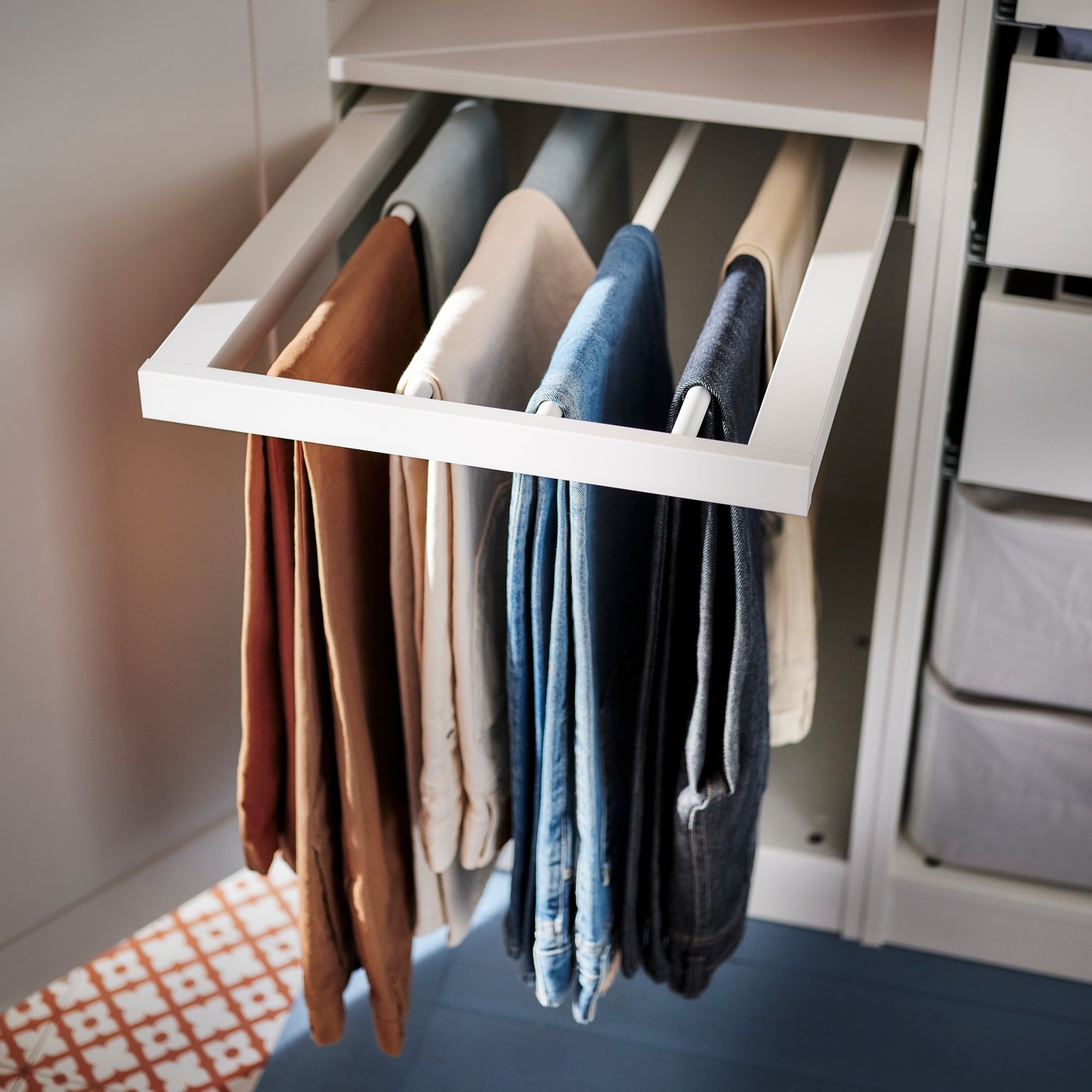 KOMPLEMENT uittrekbare broekhanger waar enkele broeken op hangen is uitgetrokken uit een PAX/TYSSEDAL kleerkast.
