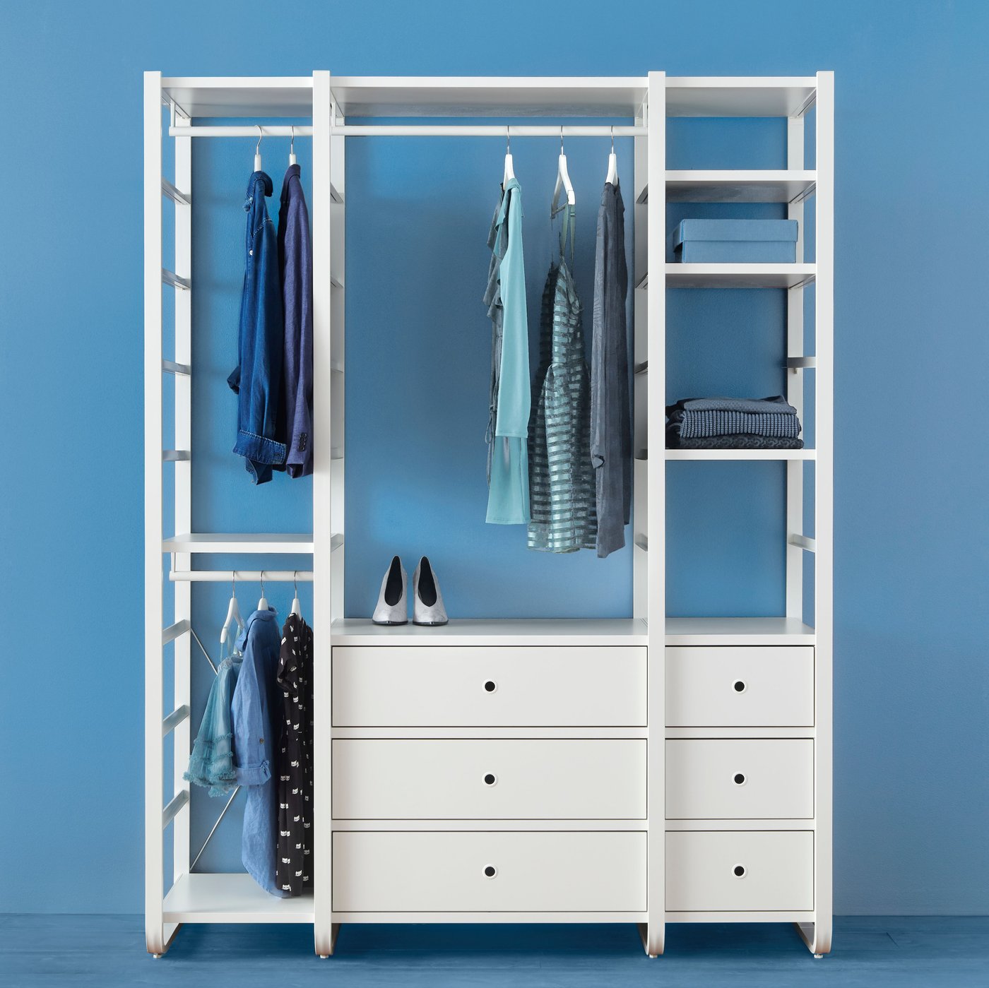 In una stanza blu, un guardaroba componibile ELVARLI con abiti appesi a un bastone, borse e altri oggetti.