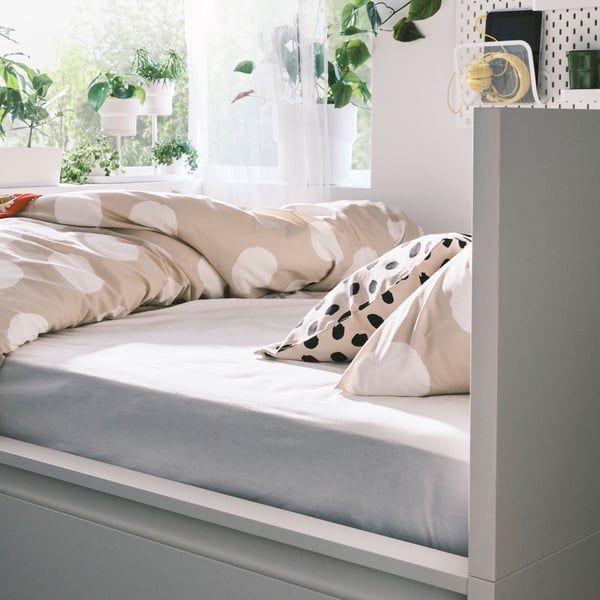Beige/white/dotted KLYNNETÅG bed linen and an off-white/black dot pattern ODDNY cushion on a white MALM bed.