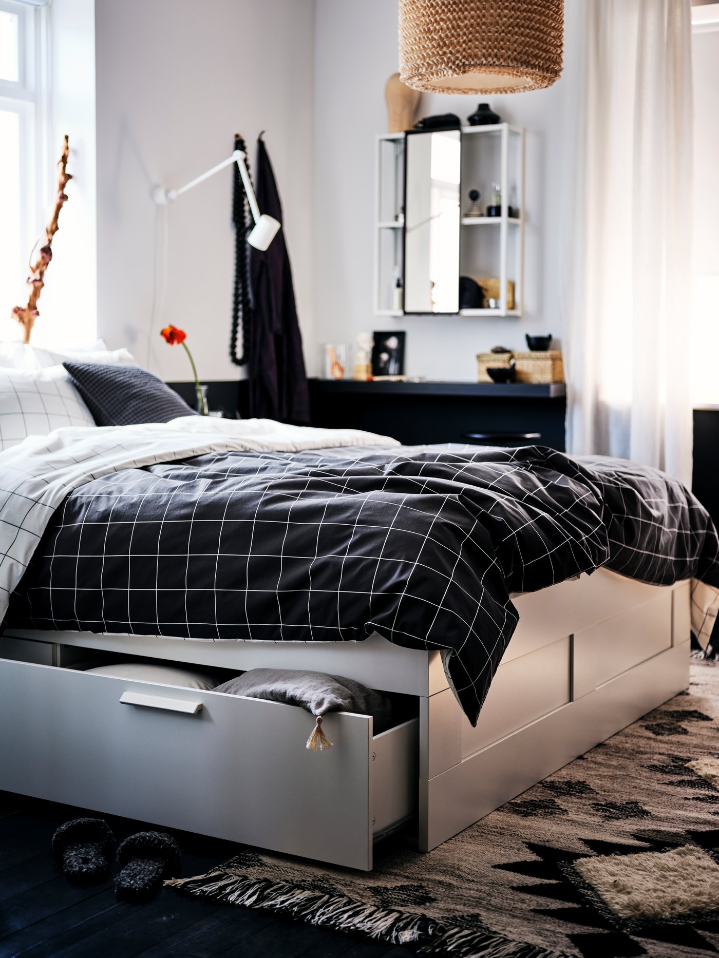 Une chambre dispose d'un lit BRIMNES blanc avec rangement réalisé avec du linge de lit VITKLÖVER à carreaux noirs et blancs.