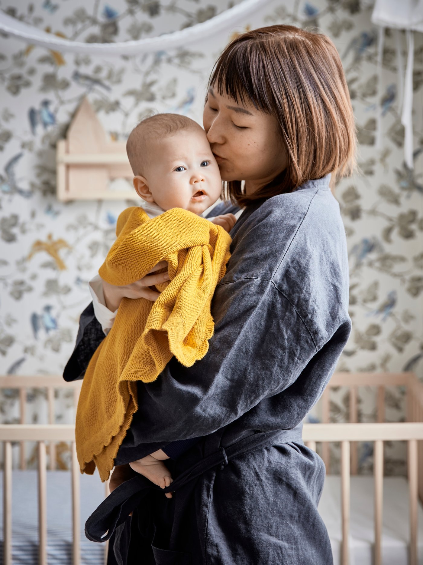 Una mamma tiene il suo bambino in braccio e gli dà un bacio sulla testolina.