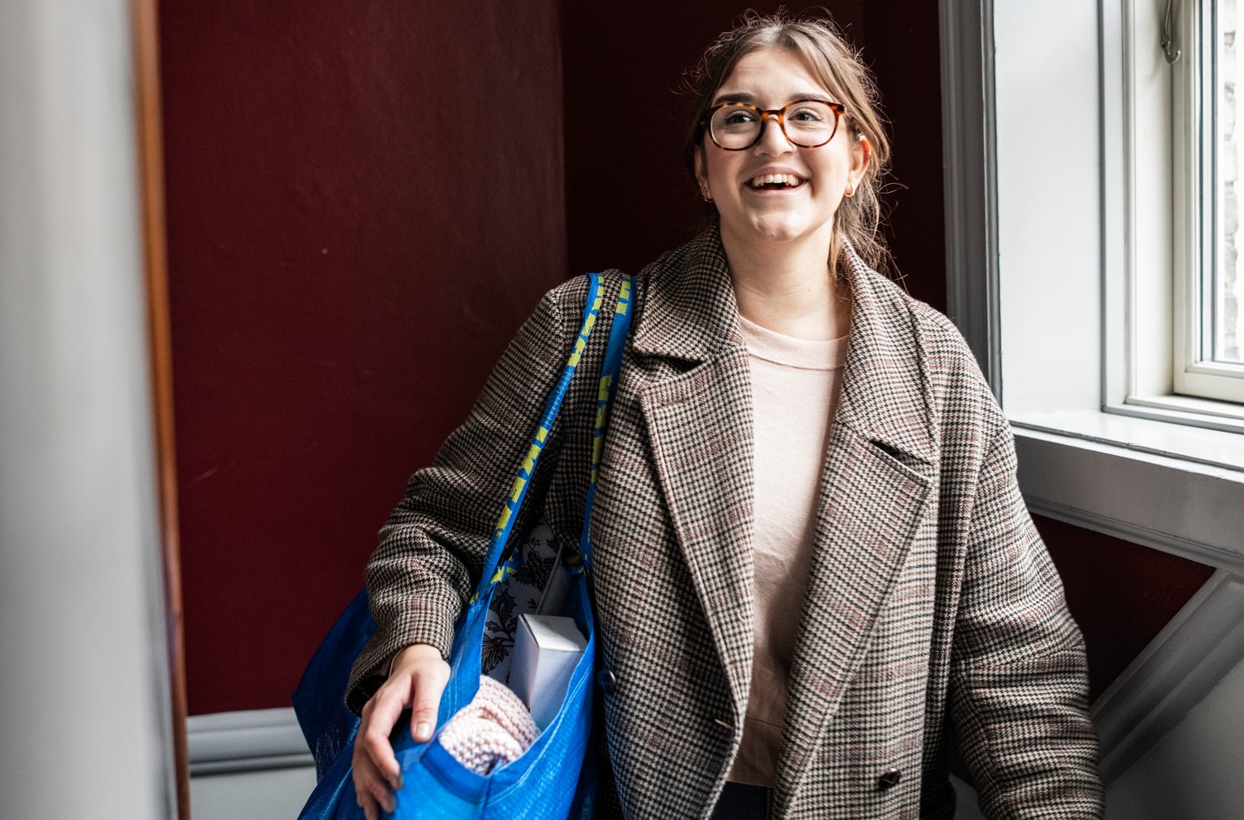 Client IKEA portant un sac de magasinage FRAKTA bleu rempli d’articles