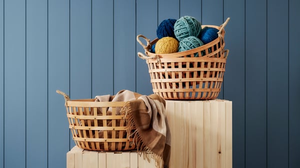 VAXTHUS storage baskets on two standees against a blue tiled wall.
