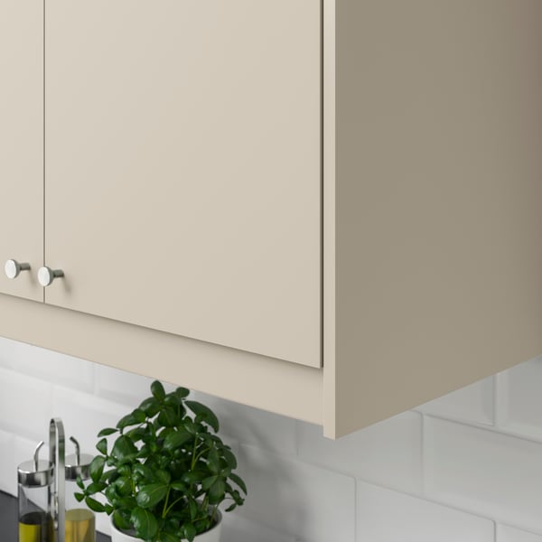 Detailní pohled na roh horní kuchyňské skříňky. Béžová dvířka HAVSTORP.