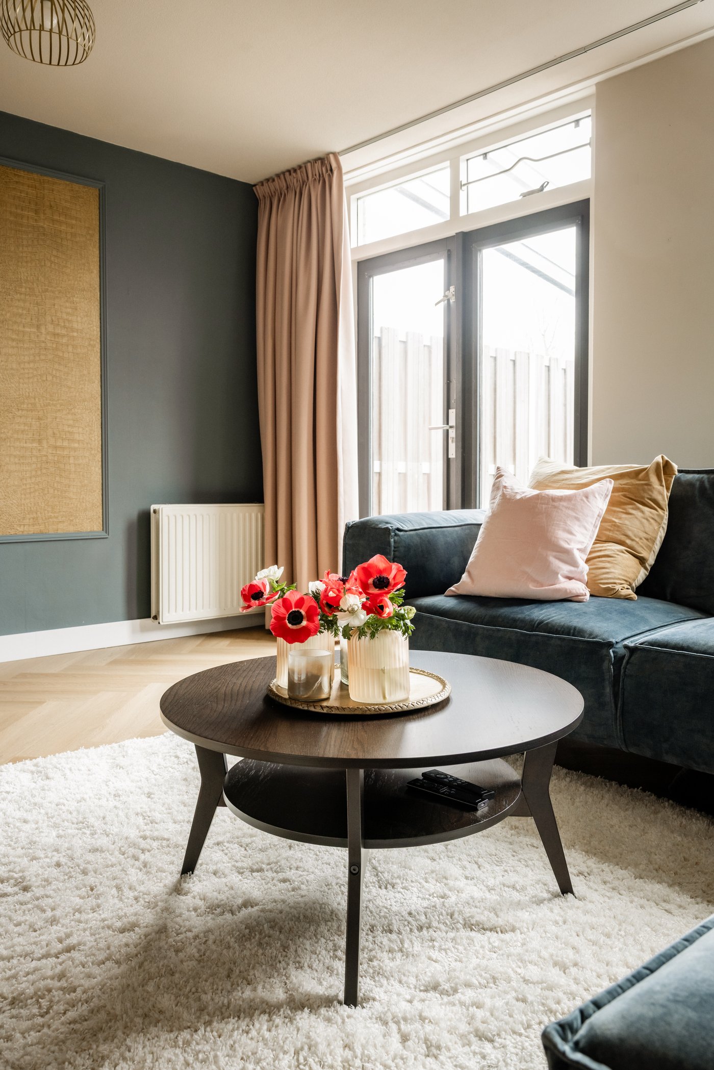 Hoek in de woonkamer met donkere hoekbank. Daarvoor staat een ronde donkere JAKOBSFORS salontafel op een wit VOLLERSLEV vloerkleed.
