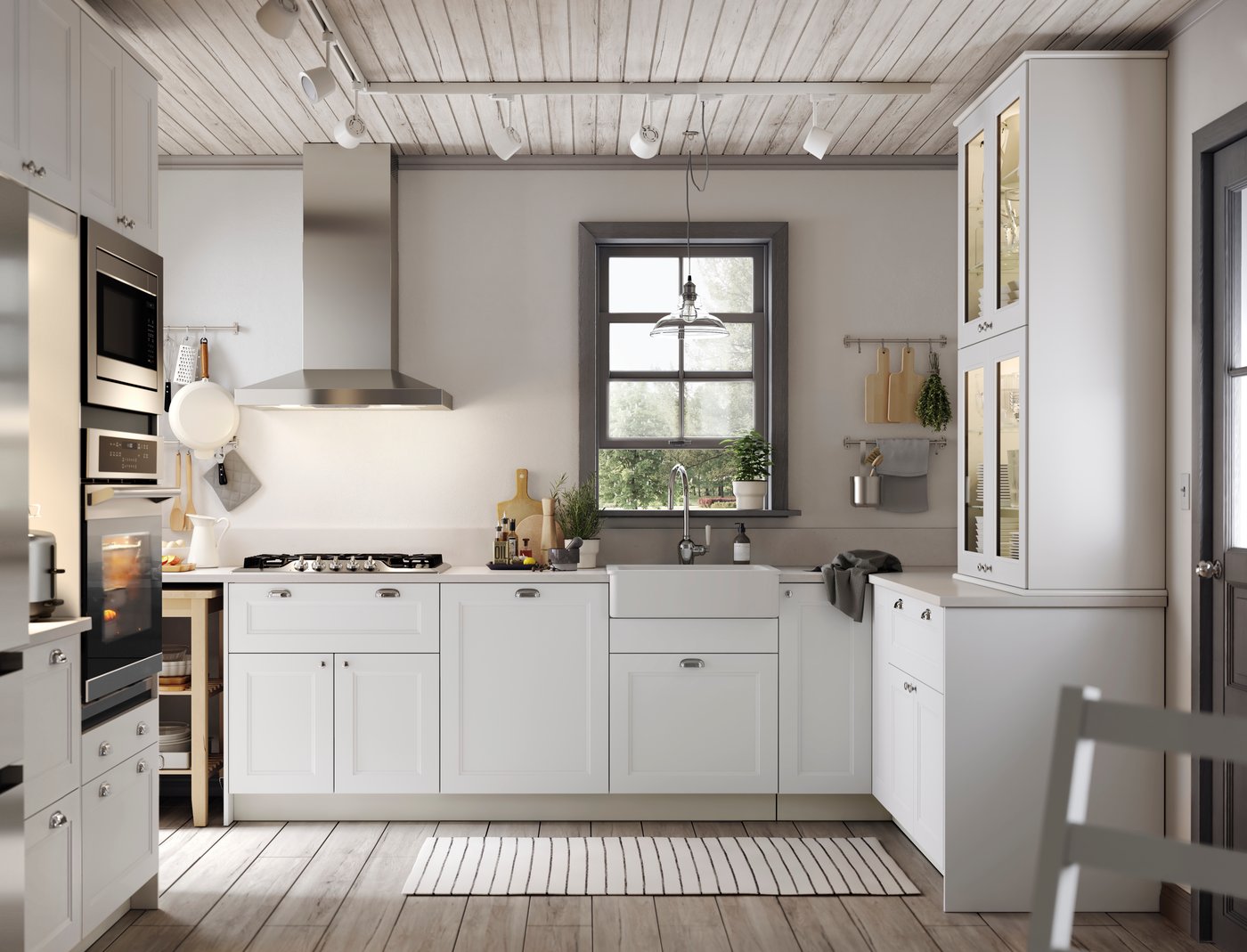 A white kitchen with white drawers and cabinets with glass doors and a stainless steel sink with a visible front.