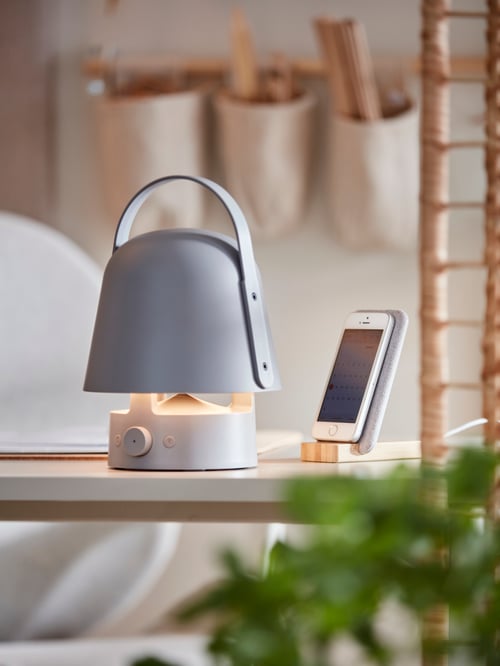 デスクの上に置いたVAPPEBY/ヴァッペビー Bluetoothスピーカーランプと、NORDMÄRKE/ノールドメルケ ワイヤレス充電スタンドに接続したスマートフォンのクローズアップ。