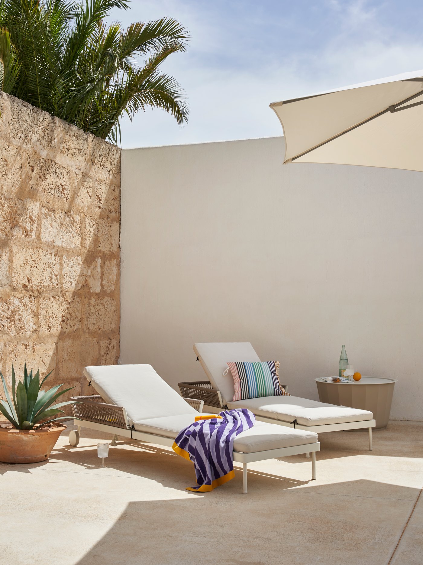 Dwa leżaki SEGERÖN stojące na patio z wysokimi ścianami.