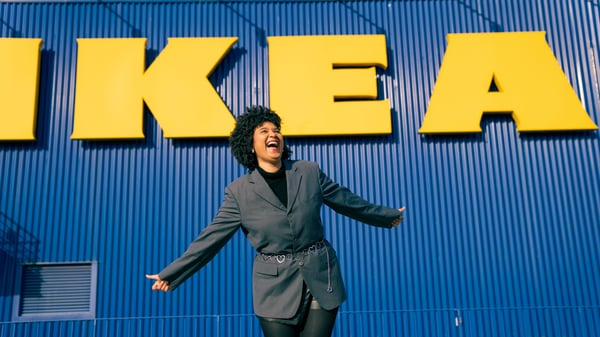 Shadia outdoors smiling with her arms out in front of the large IKEA sign.