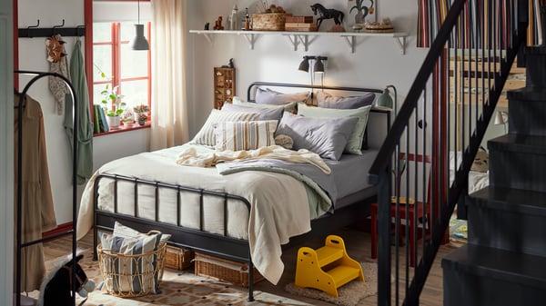 Family bedroom with STJÄRNÖ classic bedframe in anthracite with bedding in pastel colours, bright yellow step stool by bed.