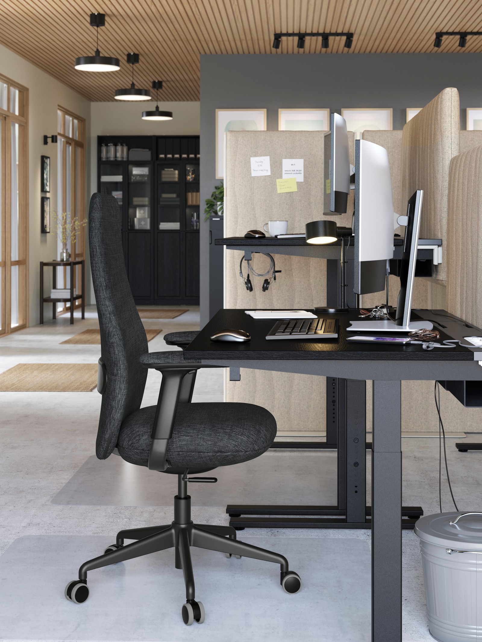 A workstation in a grey-beige office with a MITTZON desk in black stained ash veneer and a black GRÖNFJÄLL office chair.