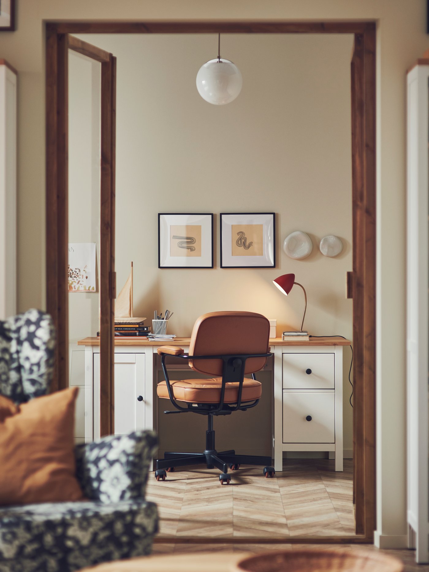Espacio de trabajo con un escritorio rectangular HEMNES, una silla de oficina ALEFJÄLL marrón y varios marcos LOMVIKEN negros.