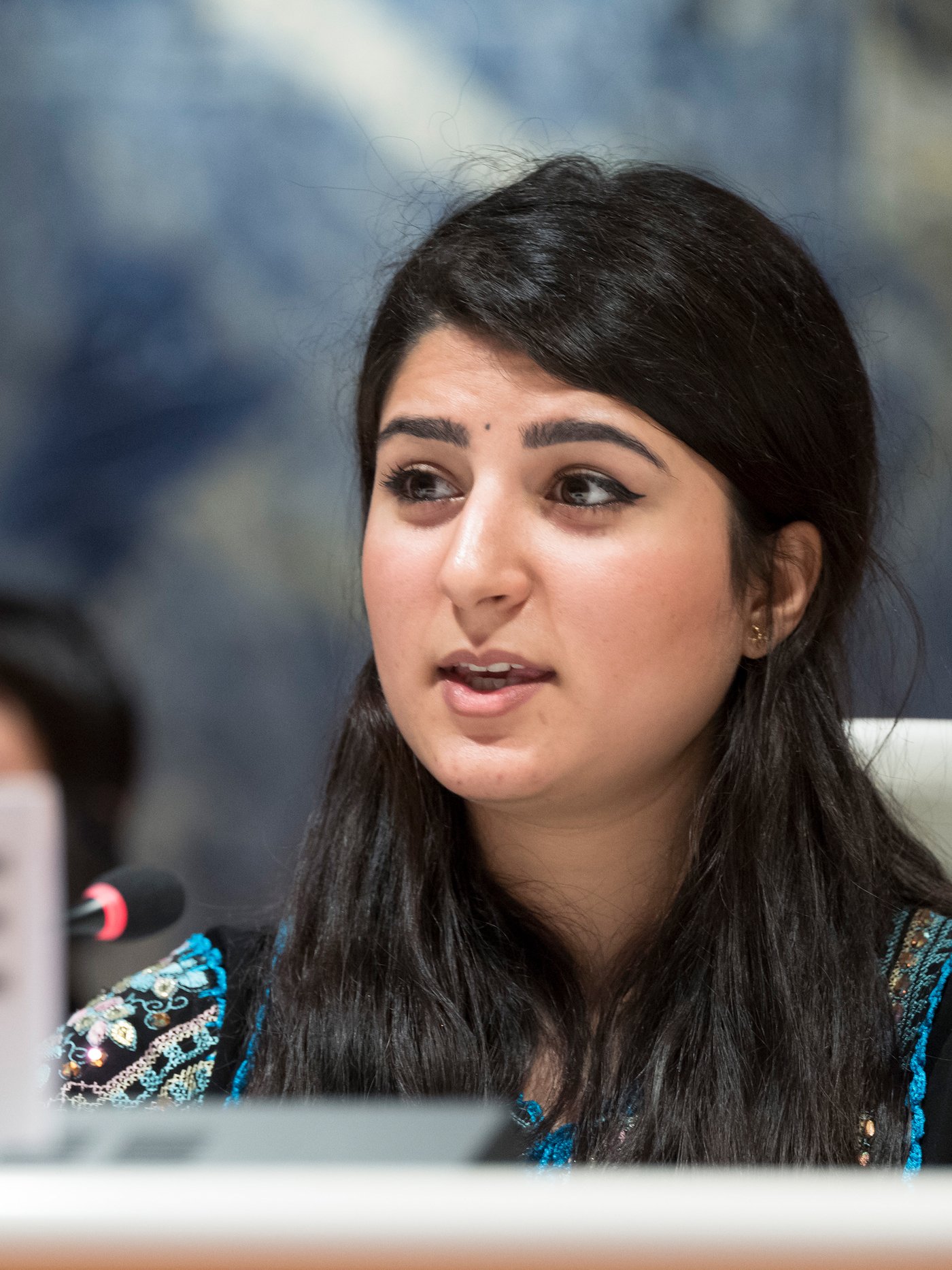 Ritratto della rifugiata irachena Aya Abdullah mentre parla da un palco.