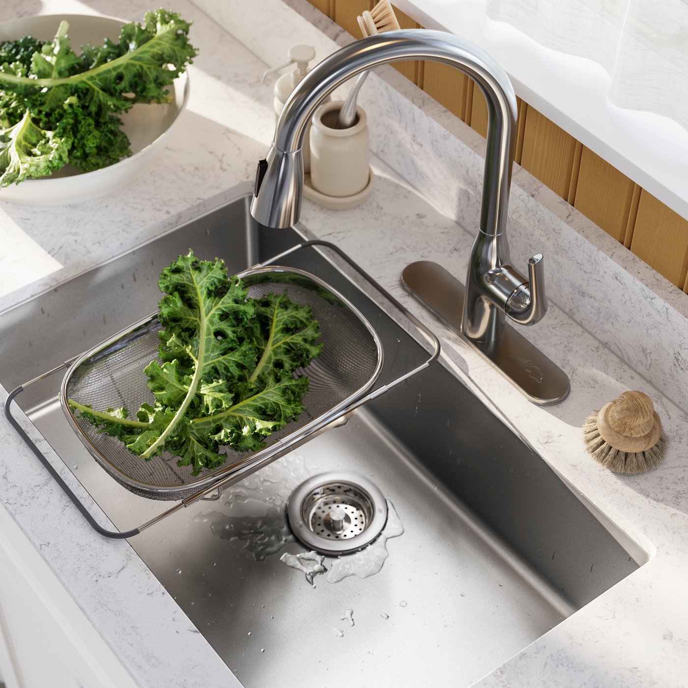 A stainless steel sink with a silver tap, holding a colander full of fresh kale and a bowl of fresh greens nearby.