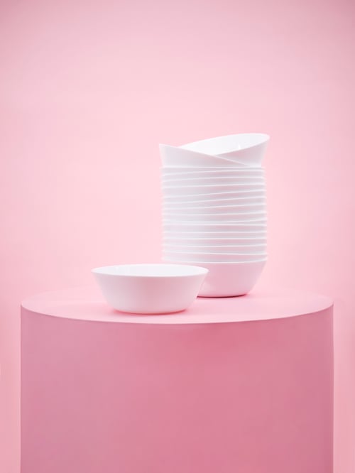 White OFTAST bowls stacked on top of each other and placed on a pink backdrop.