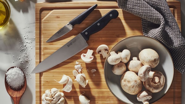 A VARDAGEN cook’s knife and a VÖRDA paring knife are placed on an APTITLIG butcher’s block of bamboo, next to some mushrooms.