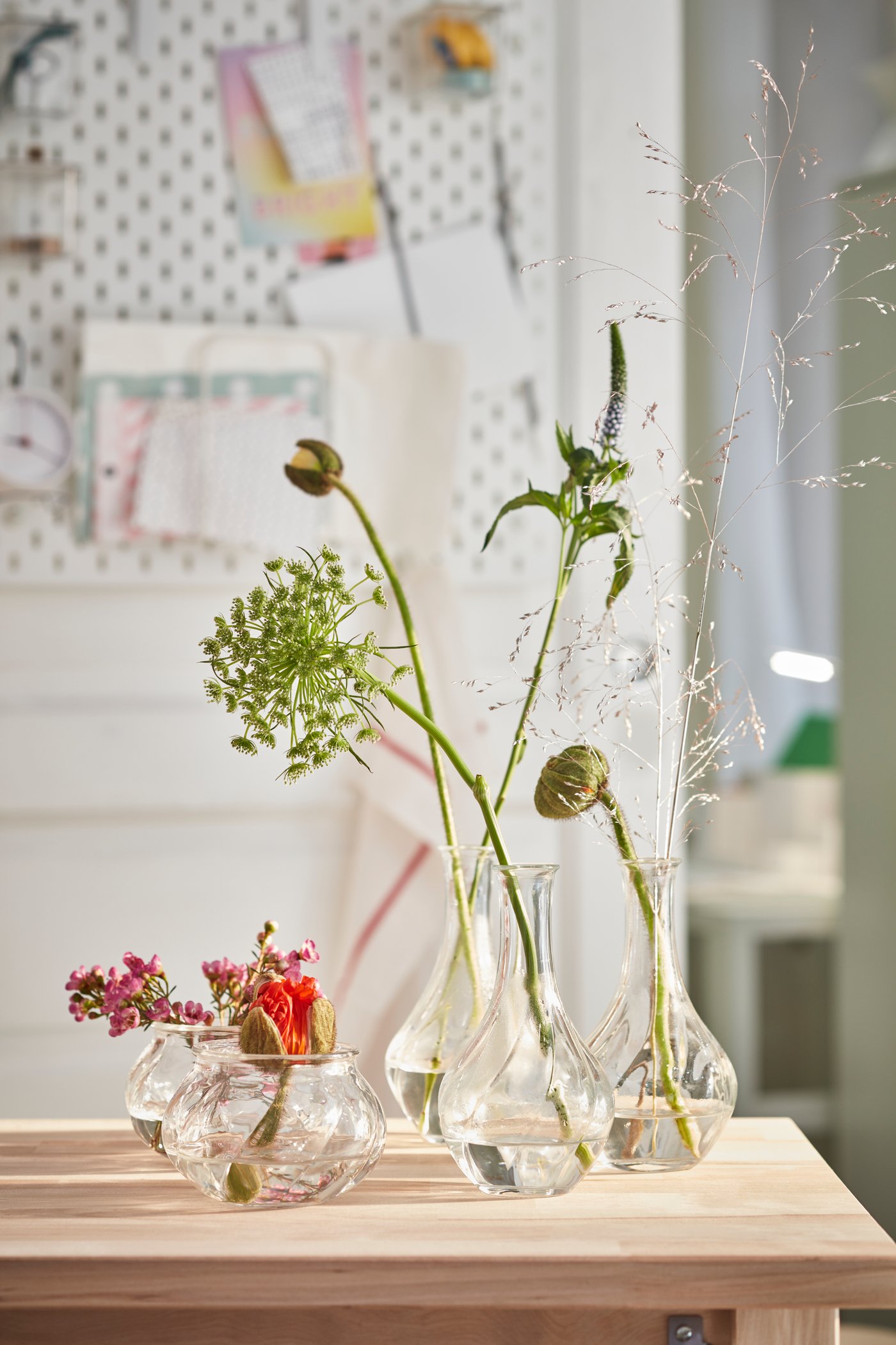 Unterschiedlich hohe VILJESTARK Vasen mit einzelnen Blüten auf einer Küchenoberfläche.