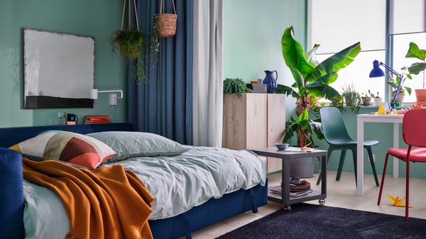 Een blauw FRIHETEN bed in een moderne en kleurrijke slaapkamer