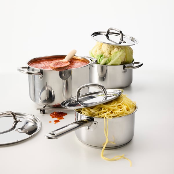 A set of 3 IKEA 365+ pots, that have been overstuffed. One with pasta, one with tomato sauce and one with a big cauliflower.