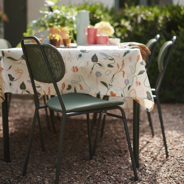 Groene eetkamerstoel ÖSTANÖ aan een zwarte tafel met een tafelkleed