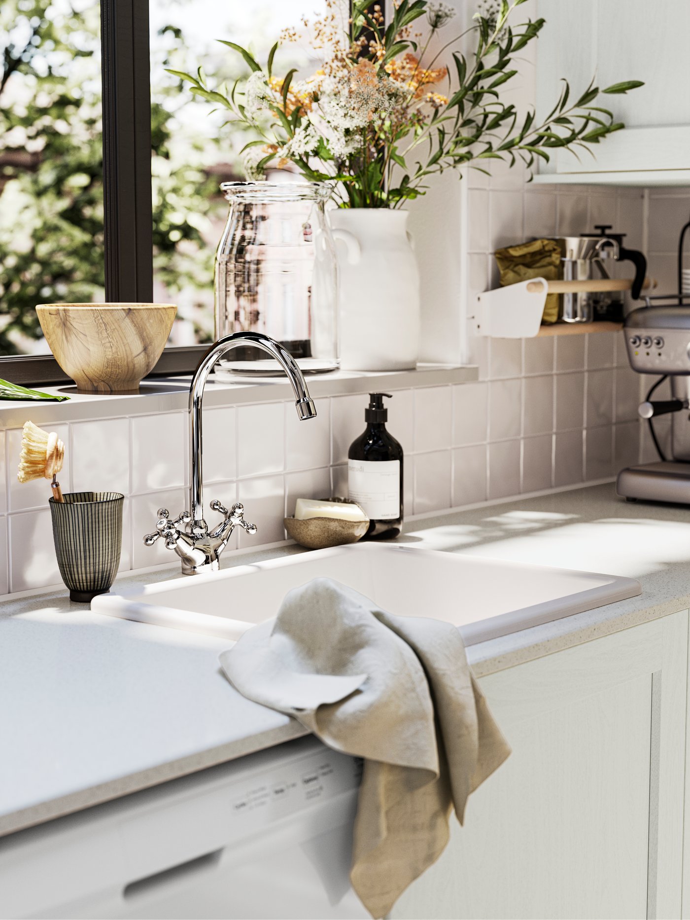 Farmhouse deco style kitchen sink with dual control mixer tap in front of windowsill with large ceramic vase of cut flowers and wooden serving bowl on it.