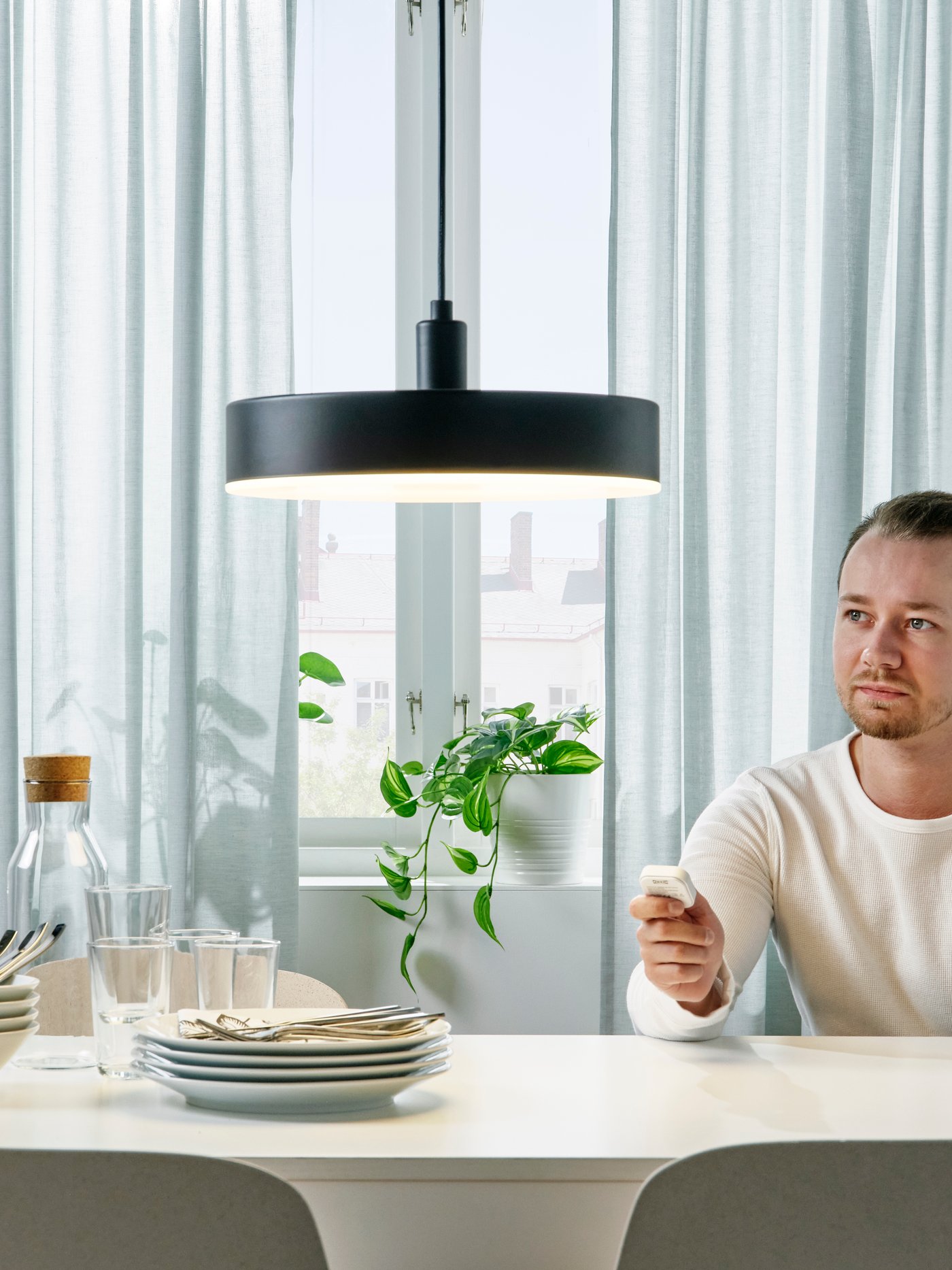 Mężczyzna sterujący lampą NYMÅNE za pomocą pilota.