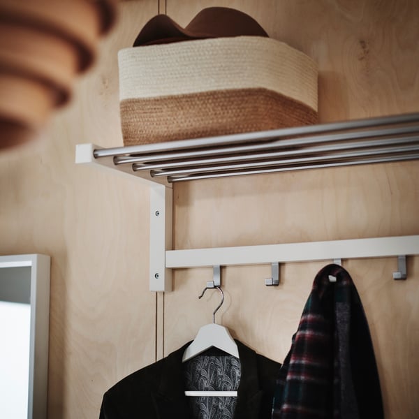 Close-up of TJUSIG hat rack with a basket on the top shelf and some jackets hanging on the hooks.