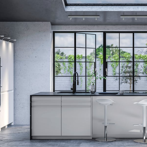 Cozinha moderna IKEA VOXTORP em branco brilhante com bancada em preto num espaço com portas grandes metálicas em preto que dão para um terraço.