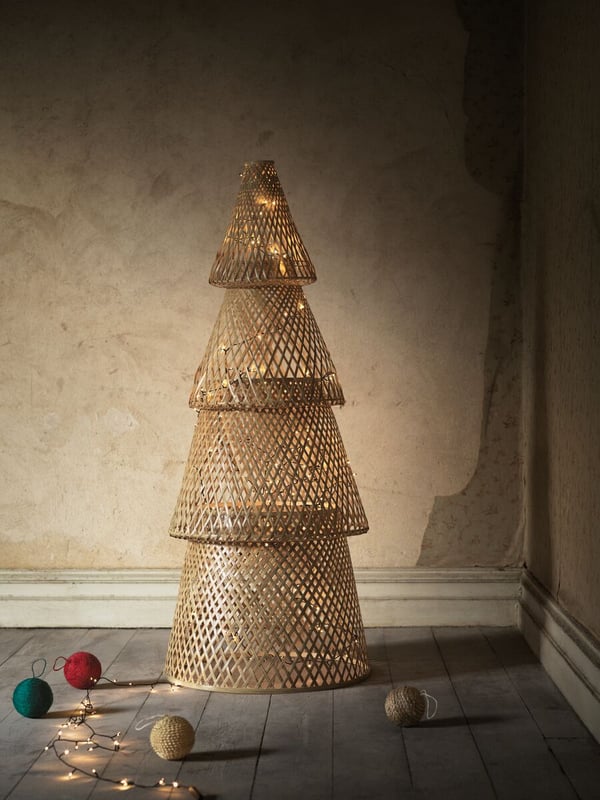 Un albero di Natale in bambù della collezione VINTER 2020 in un angolo del soggiorno illuminato da luci decorative.