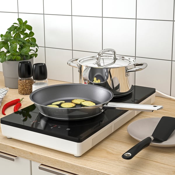 TILLREDA induction stove on top of a kitchen countertop with IKEA 365+ cookware next to a pepper and salt shakers. 