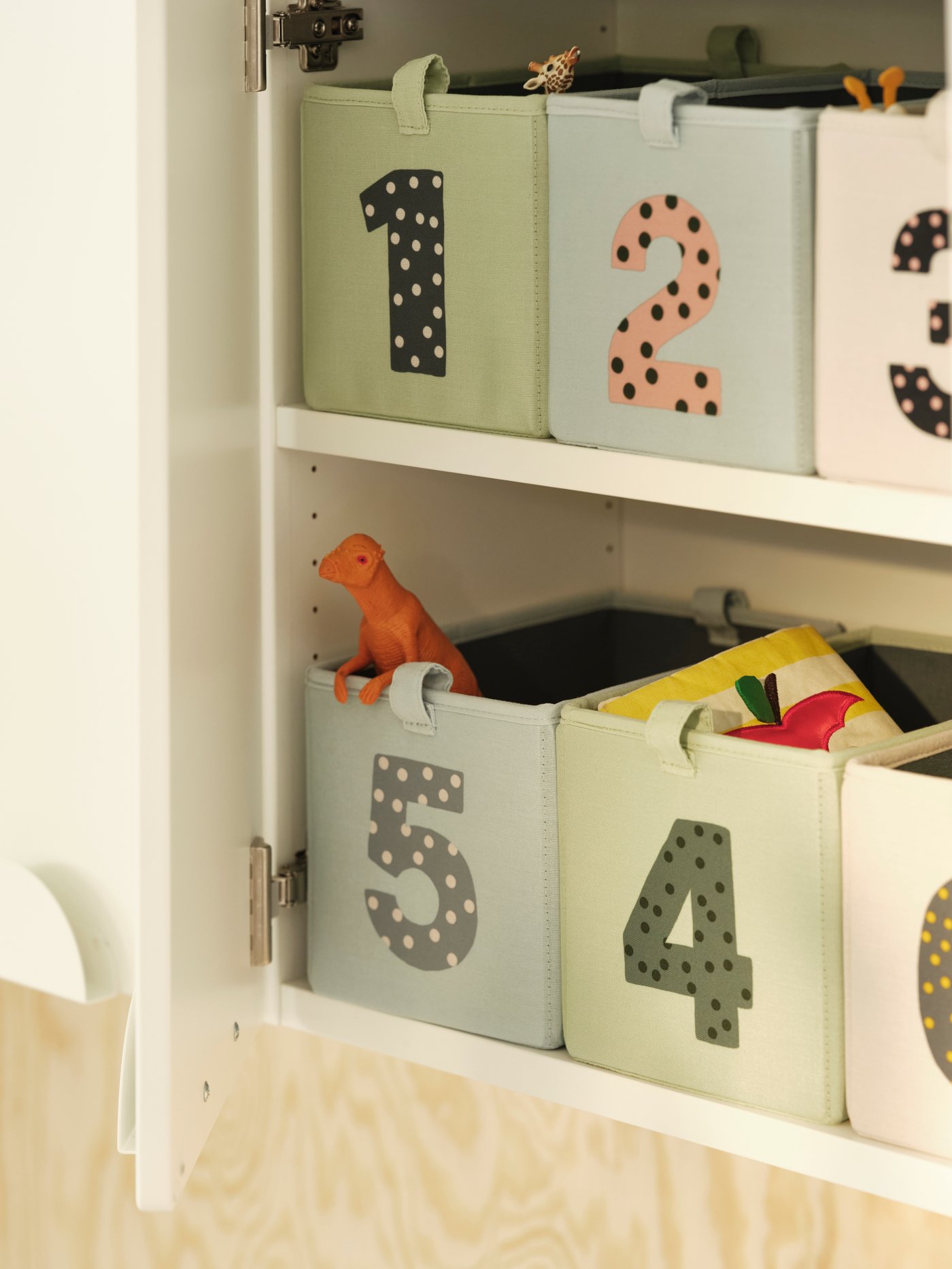 Kuusi numeroitua BARNDRÖM-laatikkoa valkoisen kaapin hyllyllä. Laatikoissa on erilaisia leluja ja vauvan tarvikkeita.