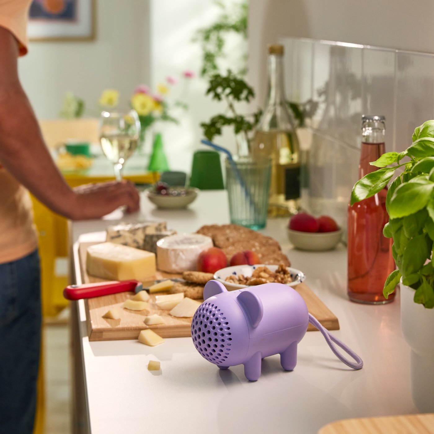 GREJSIMOJS portable bluetooth speaker, mouse/purple on the kitchen counter while a person is cooking. 