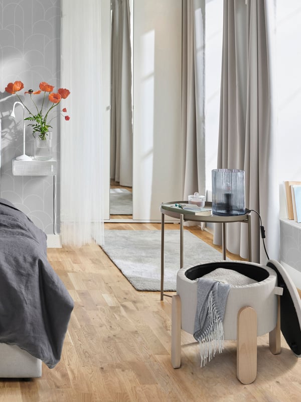 A white NÄVLINGE LED work lamp in the bedroom