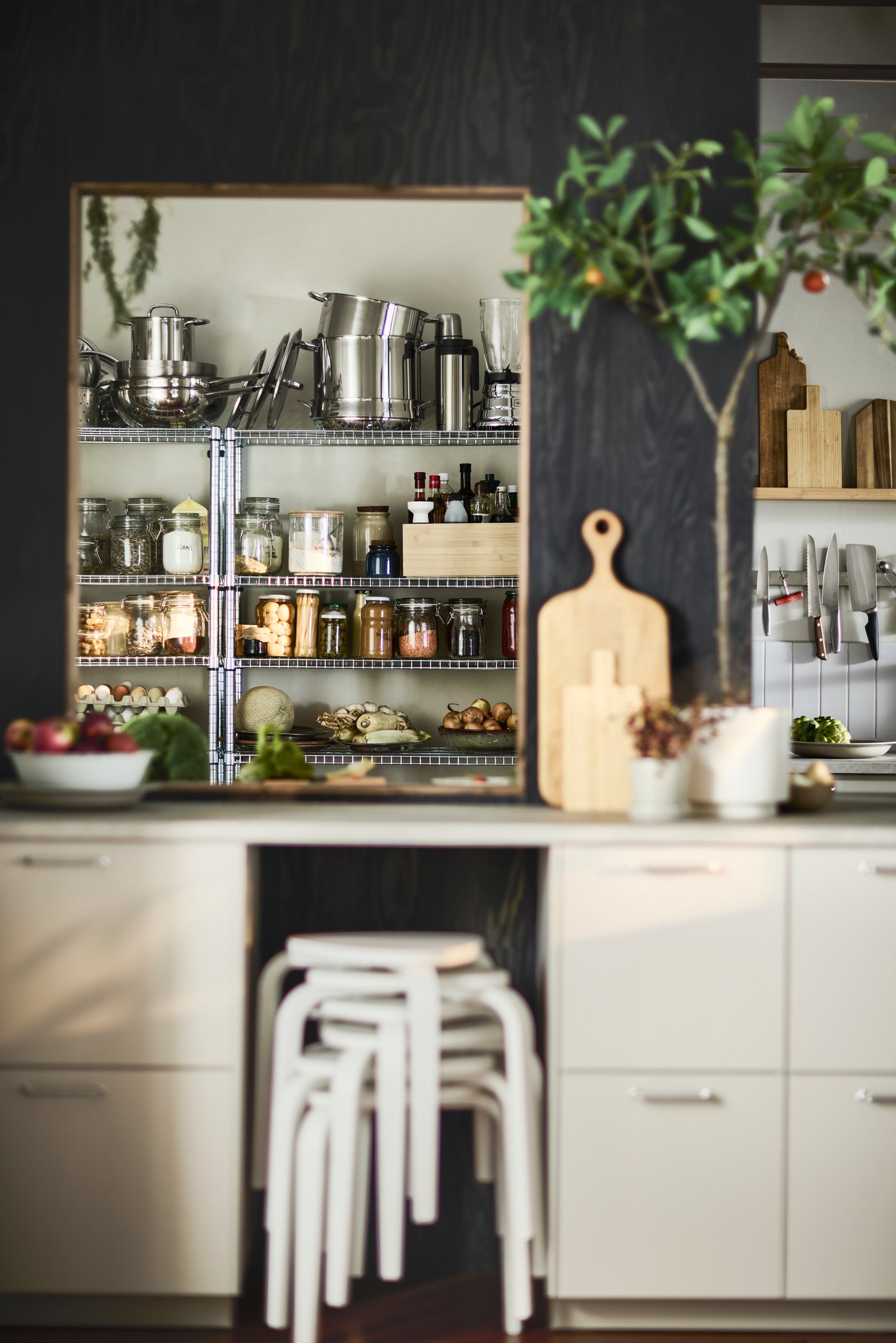 OMAR shelving units organise food, pots and pans in a kitchen with white base cabinets and black walls.