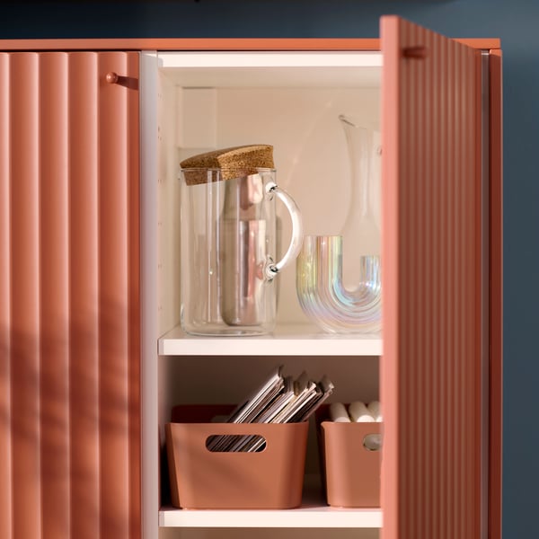 A cabinet from the METOD kitchen system has one door open and there are dinner-related items stored on shelves inside.