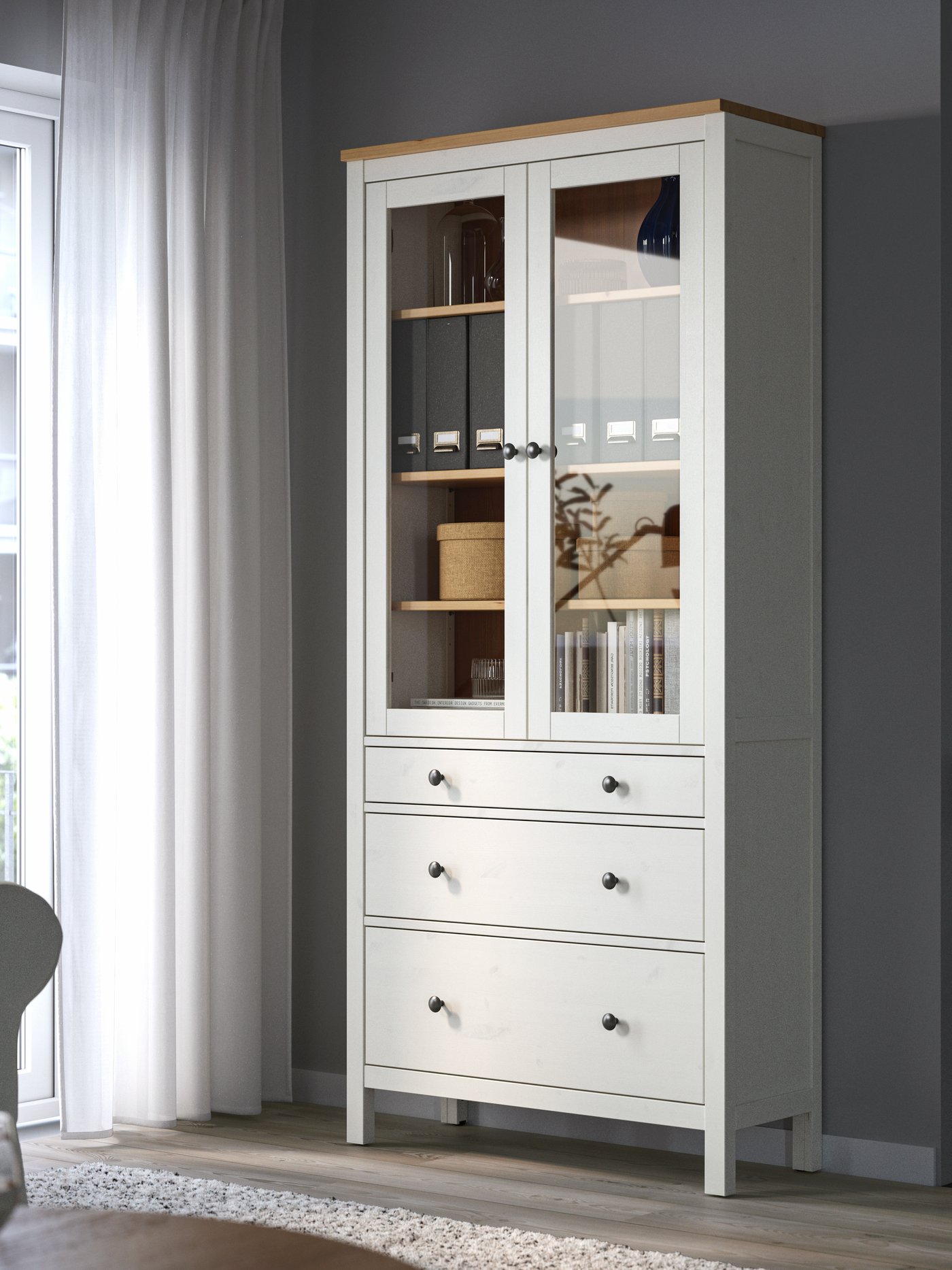 A white stain/light brown HEMNES glass-door cabinet with 3 drawers in the living room