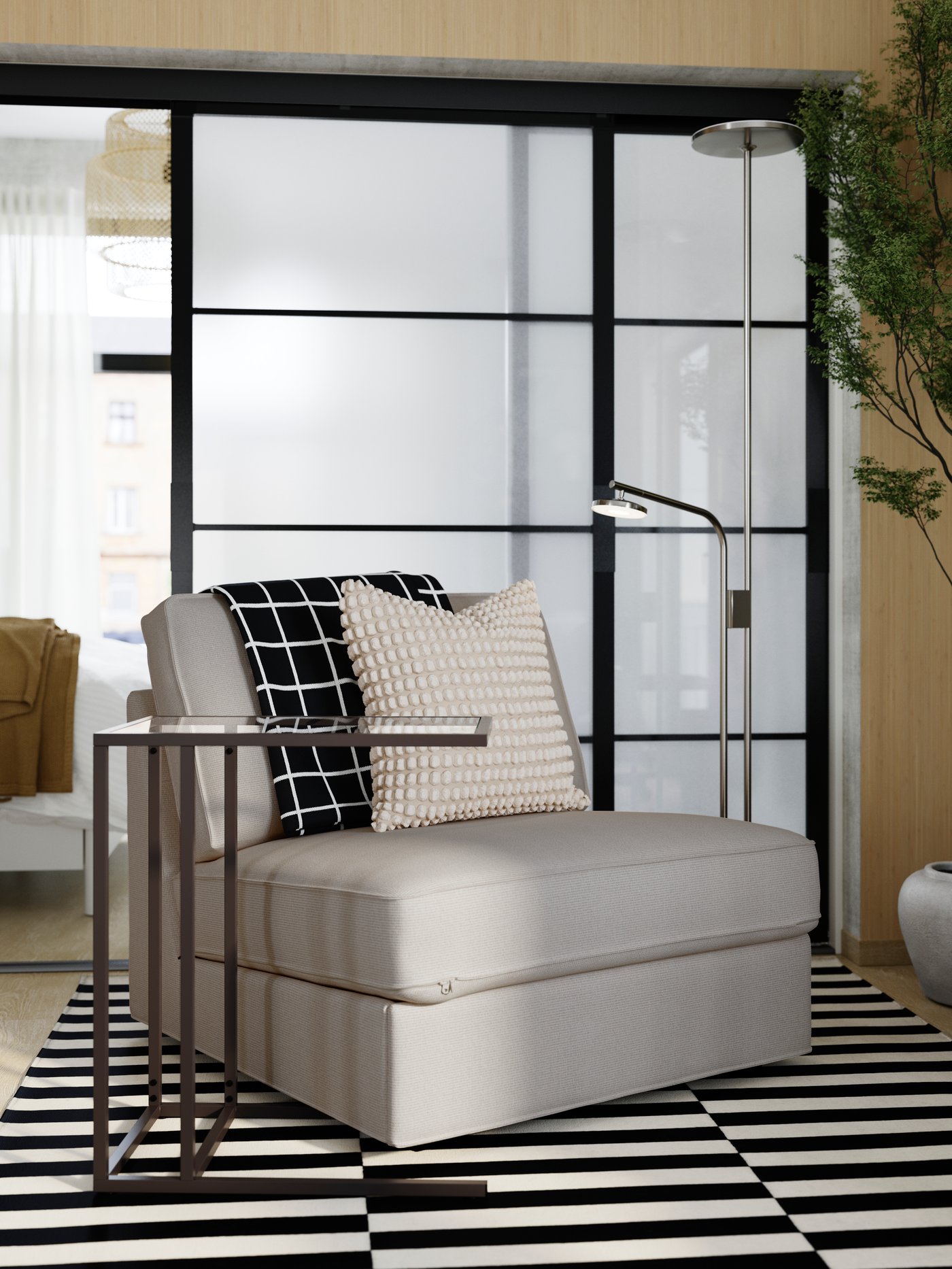 A bedroom is partly seen through open SKYTTA floor-to-ceiling sliding doors used as a room divider from a modern living area.