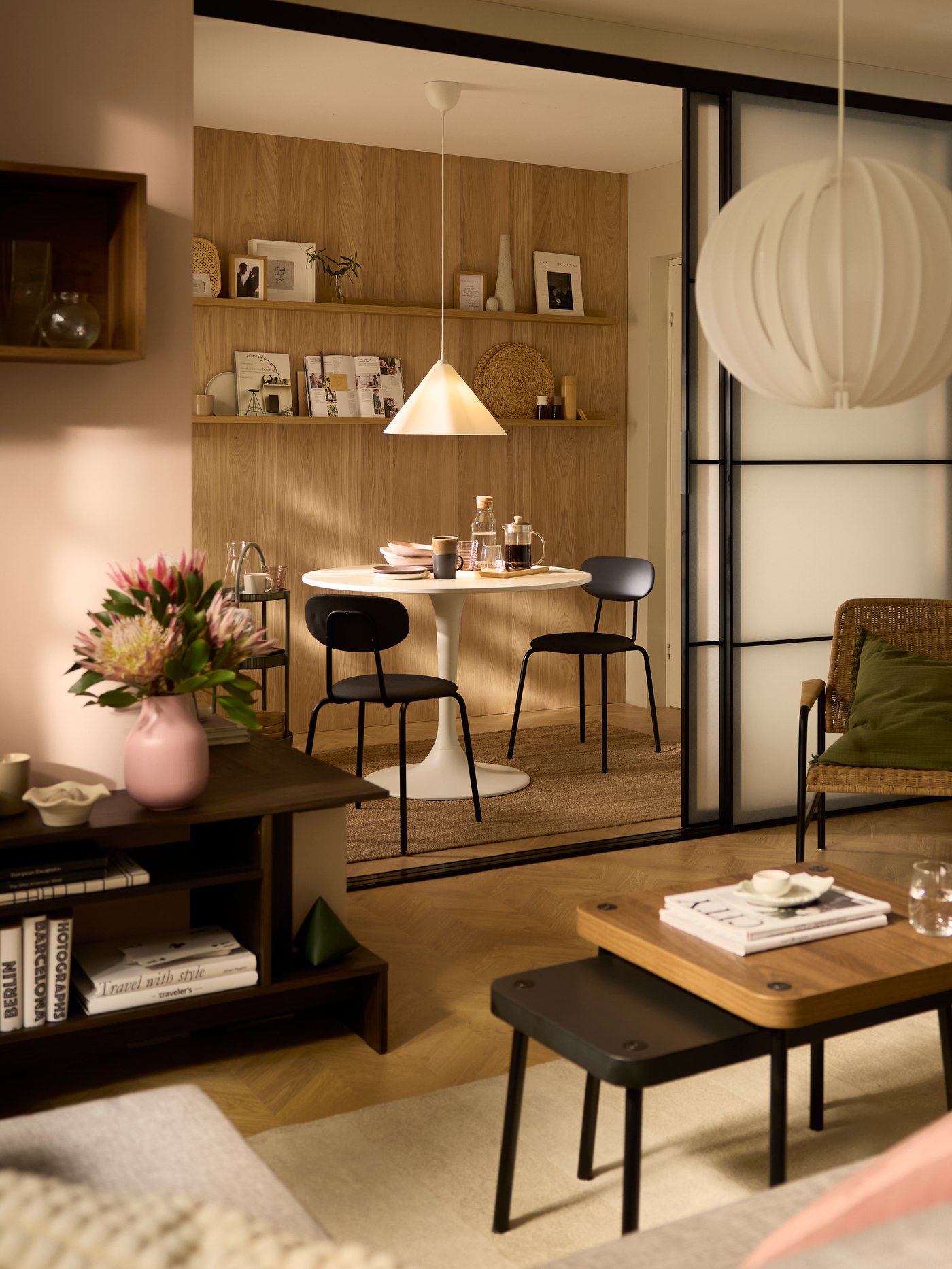 Zonovergoten woonkamer met een paar SKYTTA schuifdeuren die openstaan en uitkijken op een eethoek met een ronde DOCKSTA tafel.