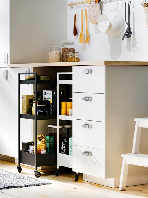 Small kitchen with white wooden base cabinets with 4 fronts, 2 low drawers and 3 middle drawers, and steel trolleys.