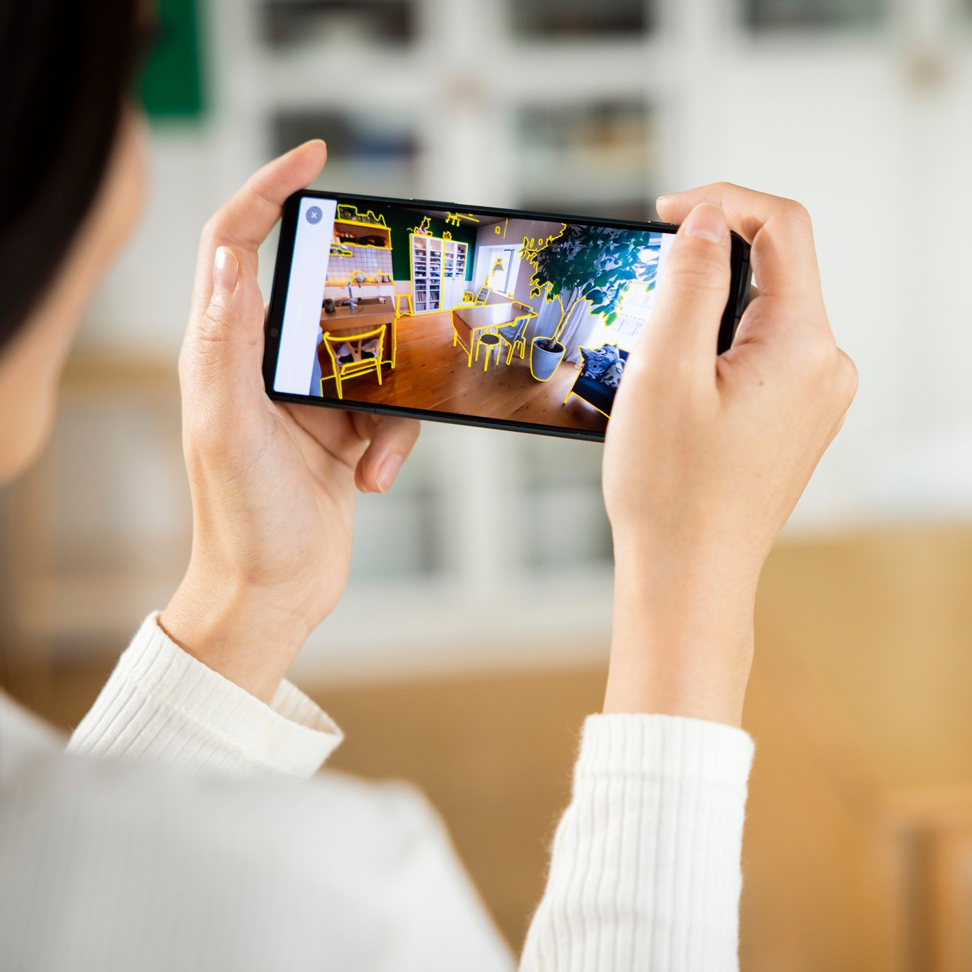 O persoană privește pe smartphone o vizualizare a unui spațiu de birouri.